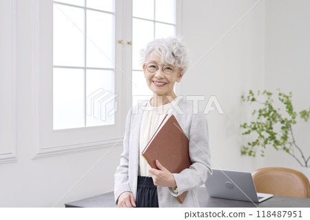 Smiling elderly businesswoman standing in the office Smiling elderly businesswoman standing in the office 118487951