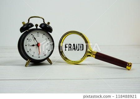 Fraud text with magnifying and alarm clock on wooden background Fraud text with magnifying and alarm clock on wooden background 118488921
