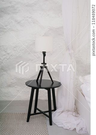 Black table lamp on a wooden table in front of a white curtain Black table lamp on a wooden table in front of a white curtain 118489072