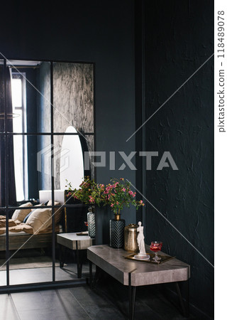 Black bedroom with a mirror and a table with a vase of flowers 118489078