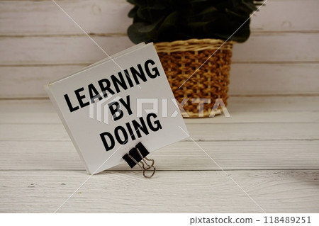 Learning By Doing text message on sticky note on wooden background 118489251