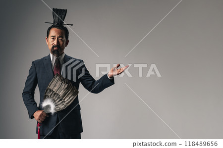 A scene where a historical Chinese military strategist, such as Zhuge Liang from the Romance of the Three Kingdoms, is introduced wearing a business suit A scene where a historical Chinese military strategist, such as Zhuge Liang from the Romance of the Three Kingdoms, is introduced wearing a business suit 118489656