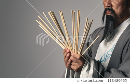 A man in Hanfu using a divining stick to read the I Ching 118489665