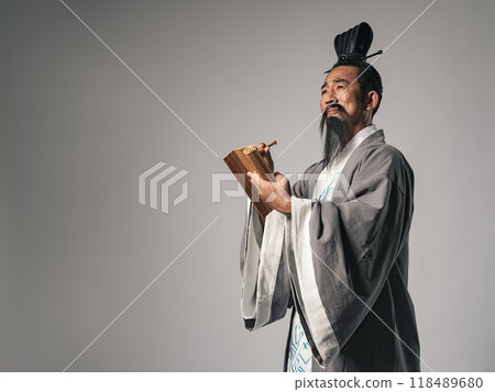 A scene in which a great figure in Chinese history, such as one from the Romance of the Three Kingdoms, writes Chinese characters on bamboo slips with a brush 118489680