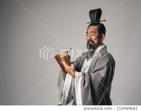 這是中國歷史上一位偉大人物,如《三國演義》中的人物,在竹簡上書寫漢字的場景。 這是中國歷史上一位偉大人物,如《三國演義》中的人物,在竹簡上書寫漢字的場景。 118489682