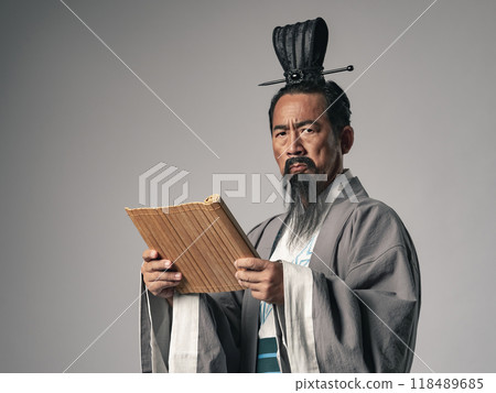 A scene of a great figure in Chinese history, such as in the Romance of the Three Kingdoms, reading a bamboo slip document 118489685