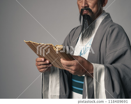 A scene of a great figure in Chinese history, such as in the Romance of the Three Kingdoms, reading a bamboo slip document A scene of a great figure in Chinese history, such as in the Romance of the Three Kingdoms, reading a bamboo slip document 118489691