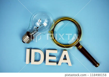 Idea word with light bulb and magnifying glass top view on blue background Idea word with light bulb and magnifying glass top view on blue background 118490158