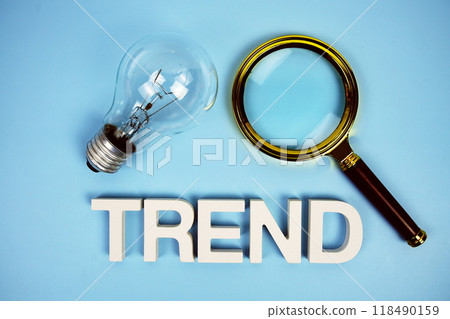 Trend word with light bulb and magnifying glass top view on blue background 118490159