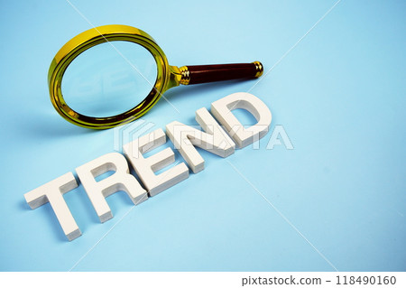 Trend word with magnifying glass top view on blue background 118490160