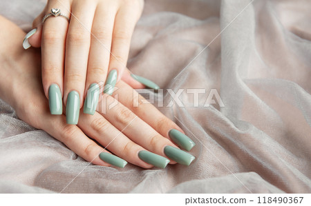 Elegant hands with long green nails resting on soft fabric Elegant hands with long green nails resting on soft fabric 118490367
