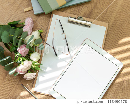 Stationery workspace with a blank tablet, notebook, and flowers on a wooden table Stationery workspace with a blank tablet, notebook, and flowers on a wooden table 118490378
