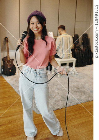 Smiling Woman Holding Microphone in Music Studio 118491315