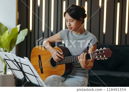 Practicing Acoustic Guitar in Cozy Living Room Setting 118491354