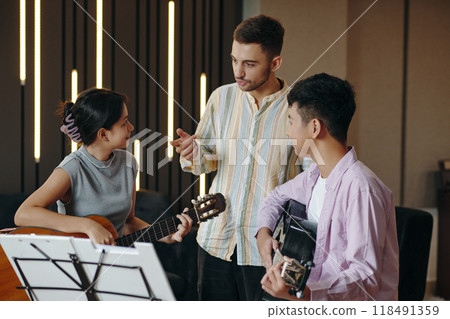 Young People Practicing Guitar in Modern Room Setting 118491359