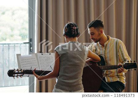 Playing Acoustic Guitar While Following Sheet Music Playing Acoustic Guitar While Following Sheet Music 118491373