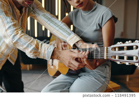Teaching Guitar to Young Woman Using Acoustic Guitar 118491395