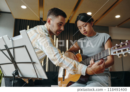 Teaching Guitar to Enthusiastic Student in Modern Classroom Teaching Guitar to Enthusiastic Student in Modern Classroom 118491400