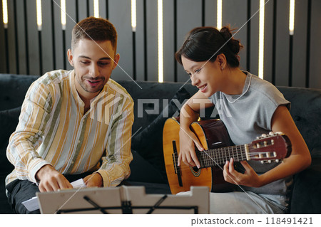 Playing Acoustic Guitar Together on Cozy Couch 118491421