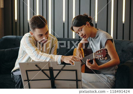 Learning Guitar with Professional Instructor Guiding Student 118491424