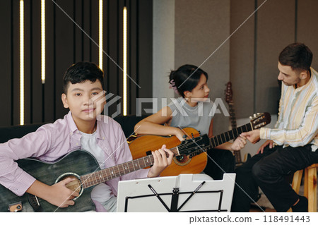 Portrait of Group Learning Guitar Together in a Cozy Room Portrait of Group Learning Guitar Together in a Cozy Room 118491443