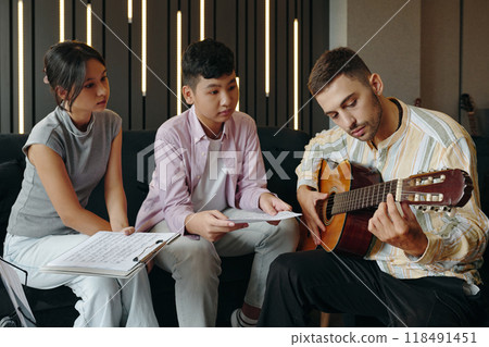 Teaching Guitar to Students Sitting in Classroom 118491451