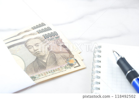 印有福澤諭吉肖像的 10,000 日元紙幣、記事本和筆 印有福澤諭吉肖像的 10,000 日元紙幣、記事本和筆 118492502