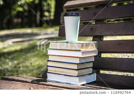 Stack of books and cup of coffee on the street in the park. Study, education, university concept. Stack of books and cup of coffee on the street in the park. Study, education, university concept. 118492764