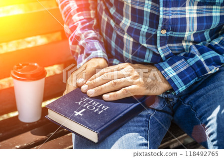Bible study. Young man reading the Bible in the park. Christian faith concept. Bible study. Young man reading the Bible in the park. Christian faith concept. 118492765