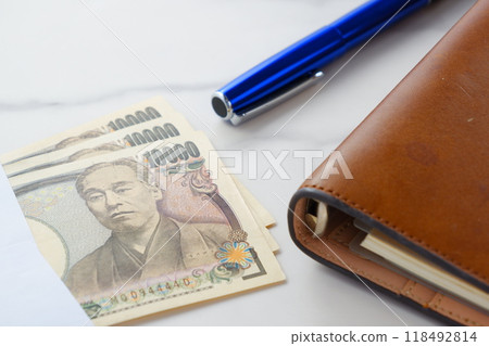 A 10,000 yen note with a portrait of Yukichi Fukuzawa and a brown leather notebook 118492814