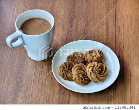 Delicious coffee-flavored cookies on a white plate and a wooden table in the morning, served with hot coffee 118493341