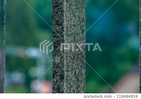 Textured Granite Fence with Blurred Greenery Background Textured Granite Fence with Blurred Greenery Background 118494859