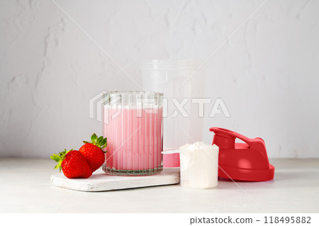 Pink strawberry protein drink shake, and protein powder in a scoop. Food supplement. Pink strawberry protein drink shake, and protein powder in a scoop. Food supplement. 118495882