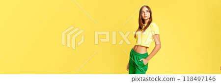 Banner. Thoughtful, dreaming young girl looking away against sunny yellow background with negative space to insert text. Banner. Thoughtful, dreaming young girl looking away against sunny yellow background with negative space to insert text. 118497146