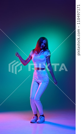 Full-length portrait of young fashionista enjoy moment and dancing in neon light against gradient studio background. Carefree. 118497171