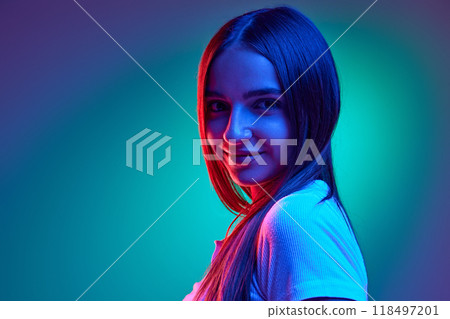Close up of attractive young girl looking at camera playfully, flirty against gradient studio background in neon lights. 118497201