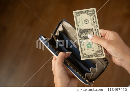 Woman taking out one dollar from her wallet 118497430