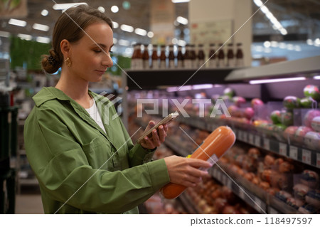 Woman choosing food products using smartphone in supermarket Woman choosing food products using smartphone in supermarket 118497597