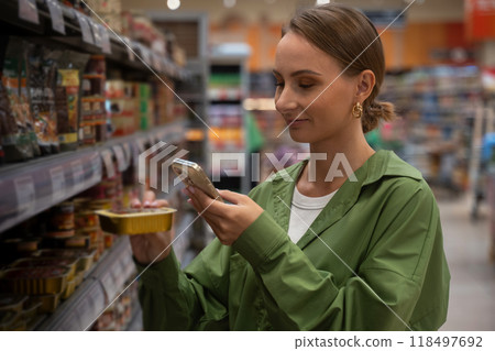 Woman choosing product using smartphone in supermarket Woman choosing product using smartphone in supermarket 118497692