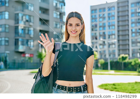 College student girl with backpack waving hand to camera, outdoor College student girl with backpack waving hand to camera, outdoor 118498299