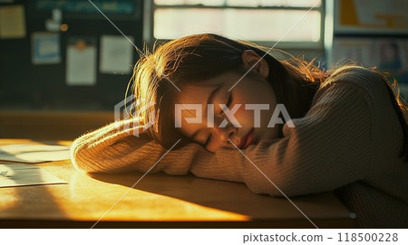 A young girl resting her head on her arms in a classroom 118500228