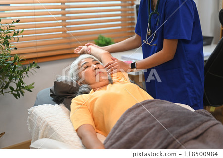 Female physiotherapist treating patient mature patient to relieve a frozen shoulder 118500984
