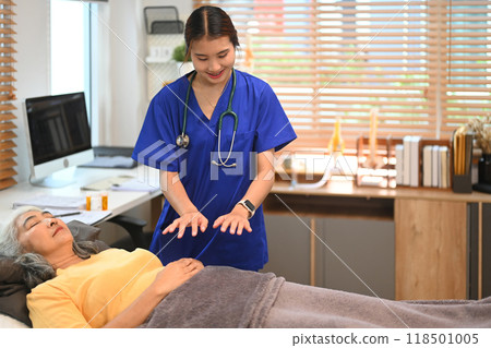 Practitioner giving Reiki healing treatment to senior woman. Alternative medicine and Reiki technique concept 118501005