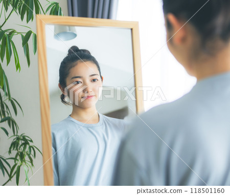 A woman in her twenties standing in front of a mirror A woman in her twenties standing in front of a mirror 118501160
