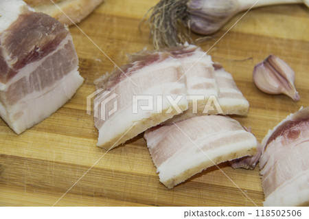 Ukrainian products raw lard with peppercorn and garlic, knife, slices salo lying on wooden board. Ukrainian traditional food concept. Ukrainian products raw lard with peppercorn and garlic, knife, slices salo lying on wooden board. Ukrainian traditional food concept. 118502506