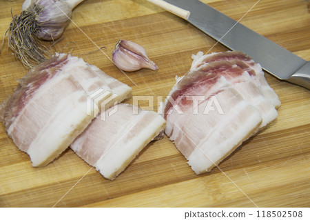 Ukrainian products raw lard with peppercorn and garlic, knife, slices salo lying on wooden board. Ukrainian traditional food concept. Ukrainian products raw lard with peppercorn and garlic, knife, slices salo lying on wooden board. Ukrainian traditional food concept. 118502508