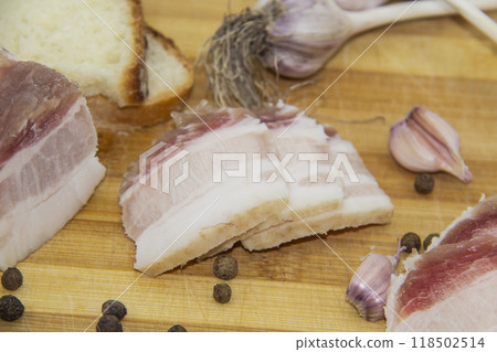 Ukrainian products raw lard with peppercorn and garlic, knife, slices of bread, salo lying on wooden board. Ukrainian traditional food concept. Ukrainian products raw lard with peppercorn and garlic, knife, slices of bread, salo lying on wooden board. Ukrainian traditional food concept. 118502514