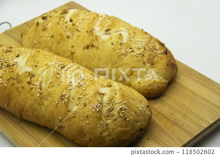 Wheat bread baked from flour at home. Tasty bread on wooden board  against background. Food with NO GMO. Homemade bread with spice on it. 118502602