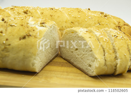 Wheat bread baked from flour at home. Sliced bread on wooden board against background. Food with NO GMO. Homemade bread with spice on it. Wheat bread baked from flour at home. Sliced bread on wooden board against background. Food with NO GMO. Homemade bread with spice on it. 118502605