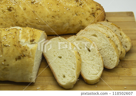Wheat bread baked from flour at home. Sliced bread on wooden board against background. Food with NO GMO. Homemade bread with spice on it. Wheat bread baked from flour at home. Sliced bread on wooden board against background. Food with NO GMO. Homemade bread with spice on it. 118502607